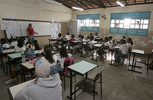 sala de aula: alunos sentados e professor de pé a frente do quadro