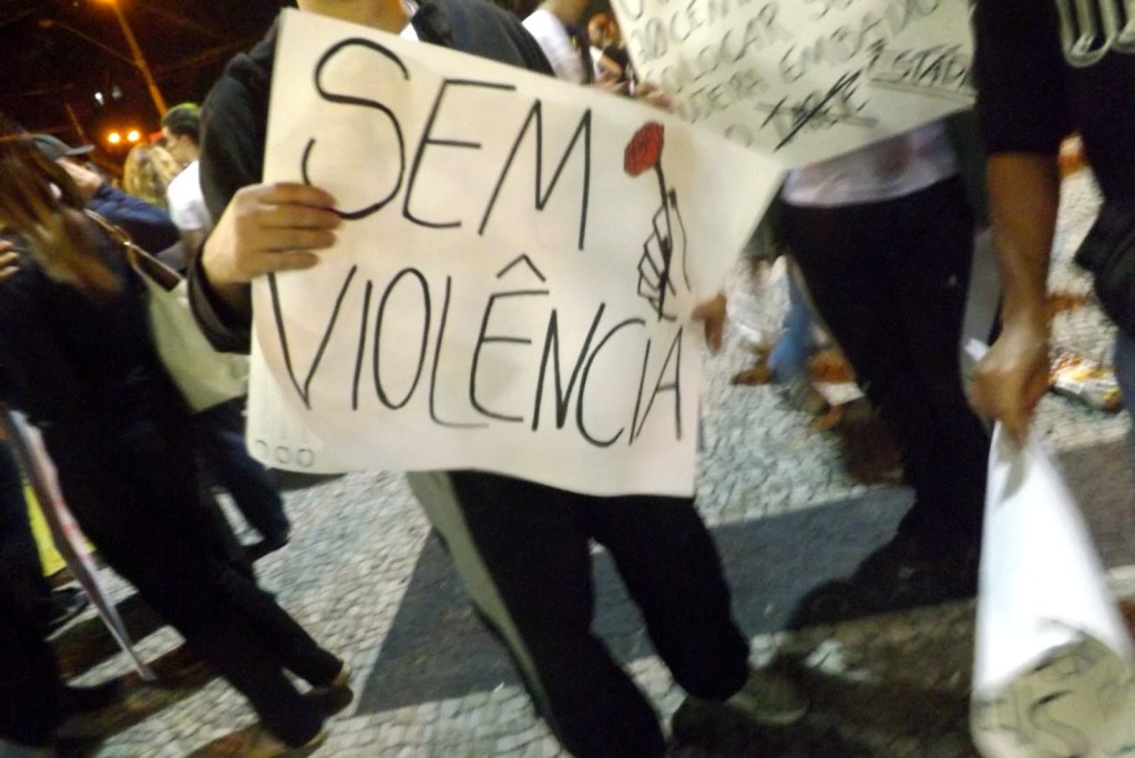uma pessoa, sem mostrar o rosto, segura um cartaz com o texto: sem violência