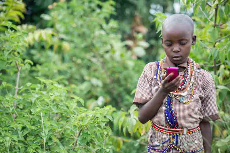 Criança segura um manipula um celular