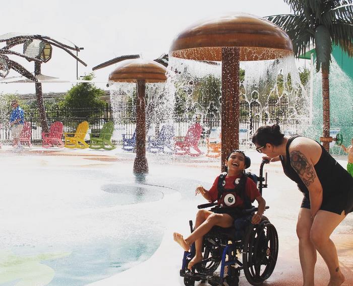 Criança com deficiência brincando em parque aquático.